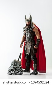 Long hair and muscular male model in leather viking's costume with the big hammer cosplaying isolated on white studio background. Full-lenght portrait. Fantasy warrior, antique battle concept.