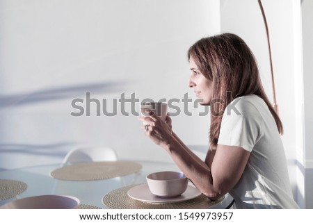 Long haired adult woman sitting on living-room while holding a cup of tea