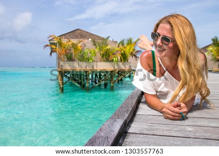 Long haired beautiful girl in front of water villas on wooden pier