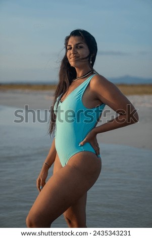 Long haired brunette woman smiling and posing on the beach