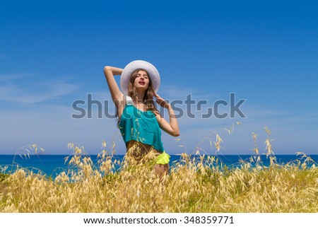 Long haired cheerful teenage brunette in beachwear, enjoys summer by the ocean.