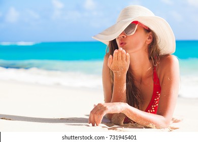 Long Haired Girl In Bikini And Straw Hat Blowing A Kiss On Tropical Caribbean Beach