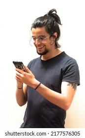 Long haired haired tattooed man with black shirt typing or viewing social media on a smartphone or mobile. White background