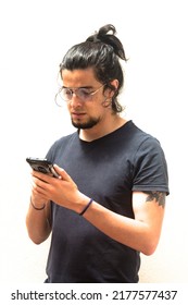 Long haired haired tattooed man with black shirt typing or viewing social media on a smartphone or mobile. White background