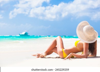 long haired young woman in bikini and sunglasses on tropical beach