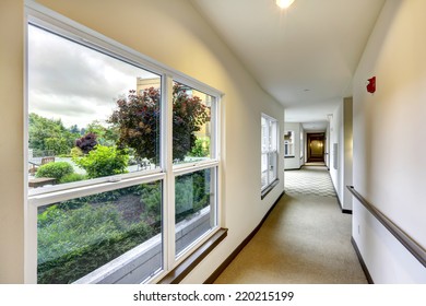 Long Hallway With Carpet Floor And Windows In Modern Residential Building.