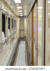 Long hallway inside a sleeper train with windows and doors to passenger cabins