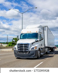 Long haul pro industrial grade big rig white semi truck with roof spoiler transporting cargo in dry van semi truck driving on the multiline highway road with green trees on the side - Shutterstock ID 1772395928