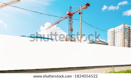 long hoarding with empty space for mock up on construction site red crane and blue sky background outside