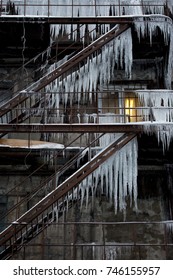 Long Icicles Hanging On The Fire Escape Of The Building/ Building Covered With Large Icicles/   Icicles On The Roofs Are Very Dangerous For People's Lives/  Dangerous Icicles Winter Concept