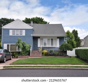 Long Island, New York, USA - September 25, 2021: Beautiful Blue And White Suburban Single Family Bungalow Split Level Home With Parked Car In Driveway.