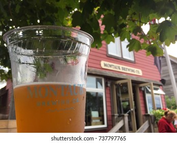 Long Island, NY - Circa 2017: Montauk Brewing Company Building In Background Of Brand Cup For Beer Sample At Outside Beer Garden To Sample And Taste New Flavor Product