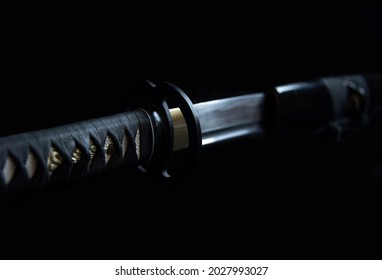 Long Japanese sword saber katana yaito. Iaido, kendo, martial arts. The art of the sword. The path of the sword. The blade of the katana is close, close-up. Katana on the black background.