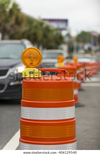 long\
line of orange traffic barrier barrels to detour traffic around\
construction zone shallow depth of field\
vertical