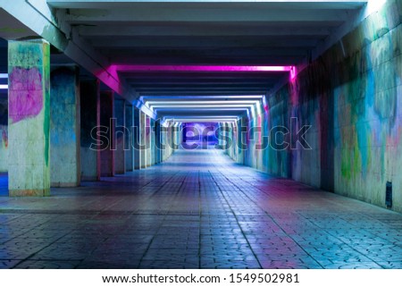 Long luminous tunnel with colorful walls. Underpass with neon lamps