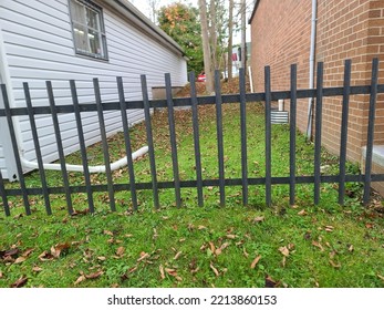 A long metal gate blocking access to the area between two buildings.