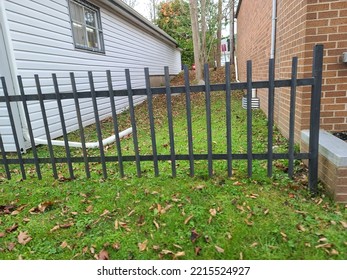 A long metal gate blocking access to the area between two buildings.