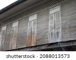 Long old antique wooden windows , doors, which are on the wall the 2nd floor of the house with wooden slats , Thailand
