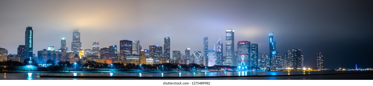 Long Panoramic View Of Chicago Skyline At Night With Top Of The Buildings Covered In Fog