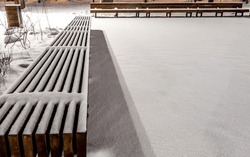 A Long Park Bench Under The Snow On A Winter Evening.
