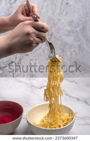 Long pasta or spaghetti on two forks in the hands of a young woman. Home cooking.