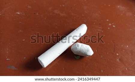 A long piece of white chalk sits on a brown base