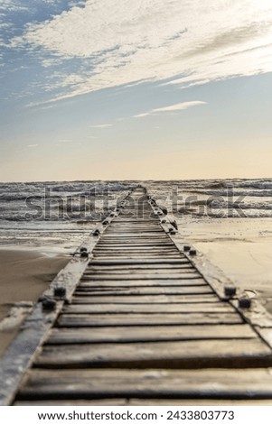 Long pier boardwalk leading out onto a Baltic sea, sunrise long way out.