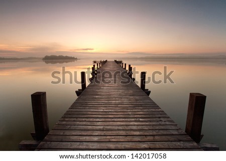 a long pier leading out onto the lake, sunrise on lake, long way out with fog
