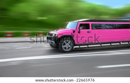 Long, pink hummer limousine on the road. Background blurred with speed.