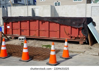 Long Red Covered Dumpster With Orange Warning Danger Cones In Front