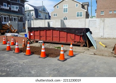 Long Red Covered Dumpster With Orange Warning Danger Cones In Front