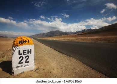 Long Road In The Desert With Mile Stone Sign Saying Leh