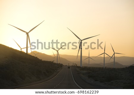 A long road going through the desert with windmills on the horizon. 