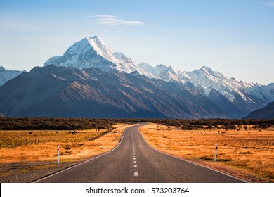 A long road leading to a large snow capped mountain on a sunny day - Powered by Shutterstock