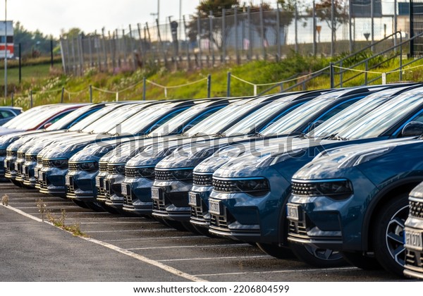 Long row of black cars ready for delivery at\
a car dealership.