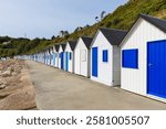 Long row of blue and white beach cabins on the boardwalk below La Corniche   hillside at Barneville-Carteret, Cotentin peninsula, France