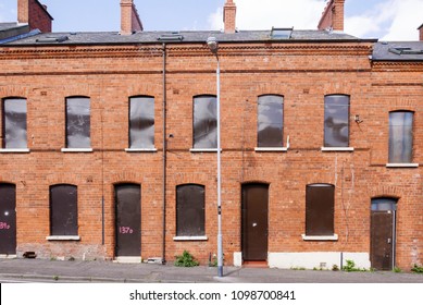 A Long Row Of Derelict Houses In A Street Boarded Up With Steel Plates.