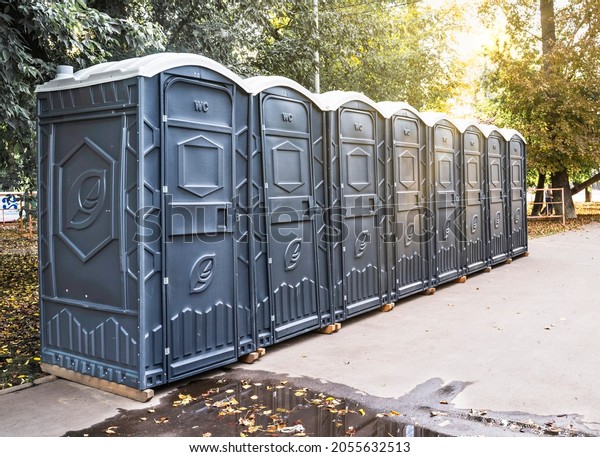 Long row of\
portable bio toilet cabins in a city street. Black cabines of bio\
toilets in the city center. Line of chemical toilets for the\
holiday, festival and crowd of people.\
WC.