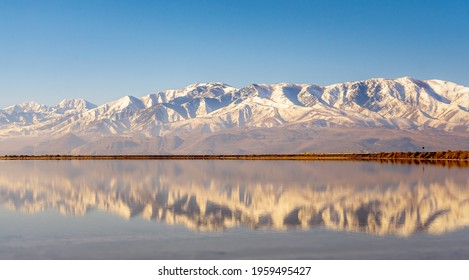 A Long Row Of Snow Covered Mountains Is Being Reflected In The Great Salt Lake That Is Just In Front Of The Mountains.