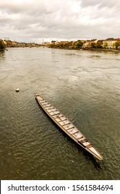 Long Rowing Boat In The Rhine River In Switzerland With Old City Center Of Basel With Munster Cathedral In The Background