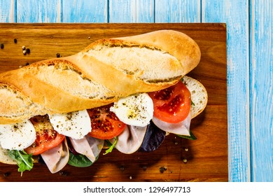 Long Sandwich On Cutting Board On Wooden Table