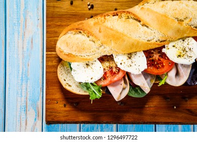 Long Sandwich On Cutting Board On Wooden Table