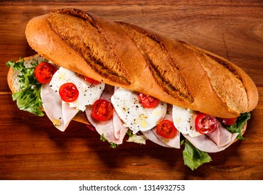 Long Sandwich On Cutting Board On Wooden Table