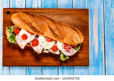 Long Sandwich On Cutting Board On Wooden Table