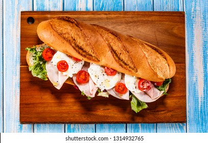 Long Sandwich On Cutting Board On Wooden Table