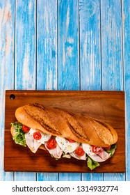 Long Sandwich On Cutting Board On Wooden Table