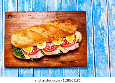 Long Sandwich On Cutting Board On Wooden Table