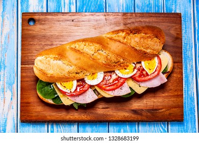 Long Sandwich On Cutting Board On Wooden Table