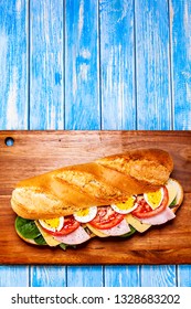 Long Sandwich On Cutting Board On Wooden Table