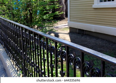 Long Section Of Scroll Work In Black Wrought Iron Fencing That Runs Along Property Lines.